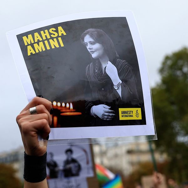 En demonstrant håller upp ett porträtt av Mahsa  Zhina Amini under en demonstration i Paris till stöd för de iranska protesterna efter Aminis död.