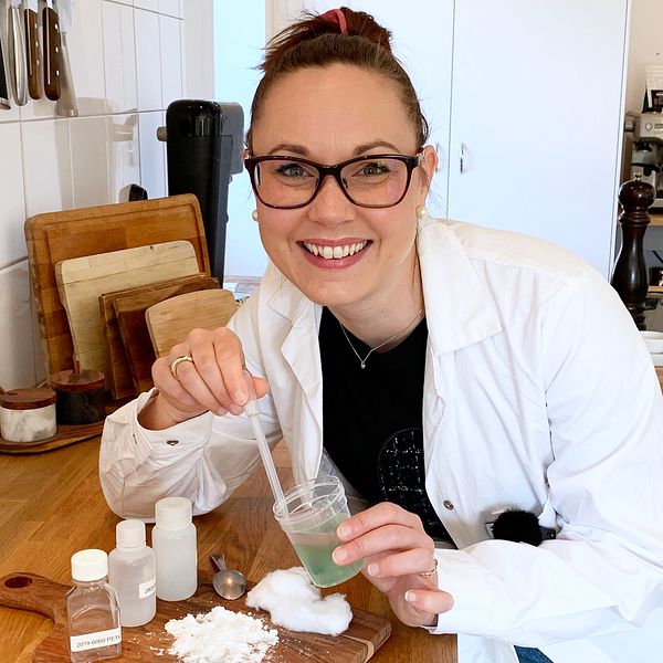 Kemisten Johanna Thompson står i labbrock med redskap till ett experiment