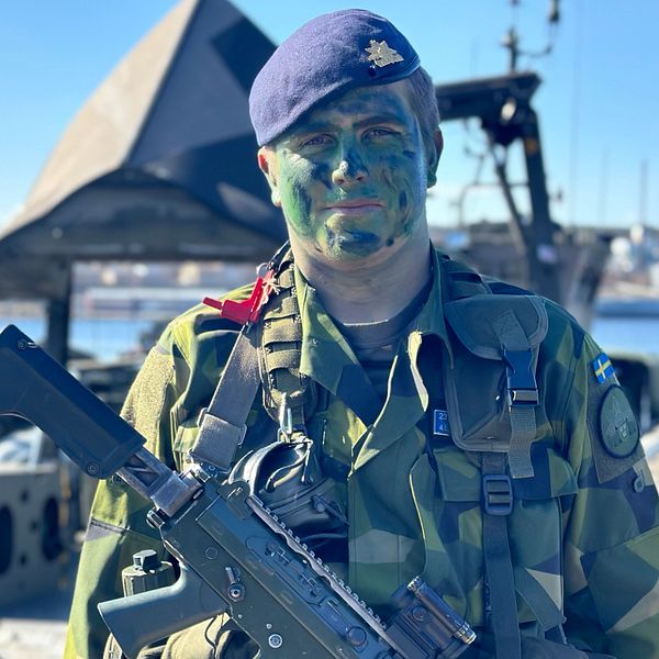 Jesper Sjögren från Sundsvall står på kajen i Härnösand i grön militäruniform, basker och kamouflagemålat ansikte. Han gör lumpen på Stockholms amfibieregemente.