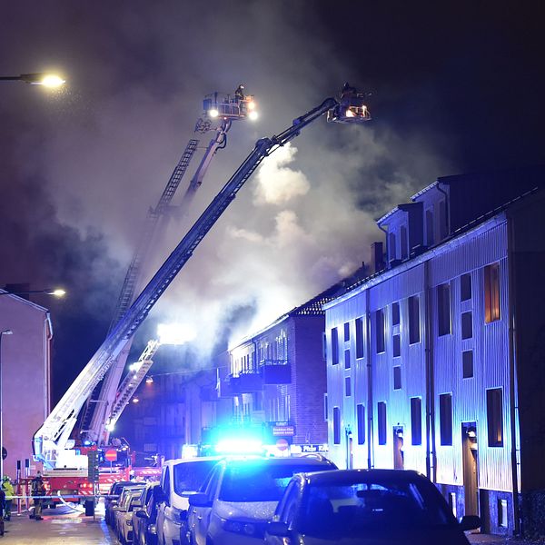 Brandmän sprutar vatten över den brandhärjade byggnaden från två stegbilar.