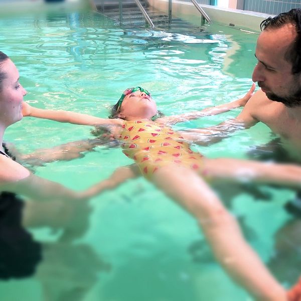 En pappa och hans barn får lära sig att simma i en pool.