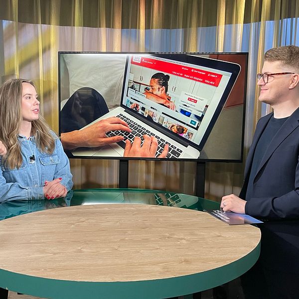 gästen står tillsammans med en tolk i studion och pratar med programledaren. I skärmen bakom studiobordet syns en person som använder 1177.se på en bärbar dator.