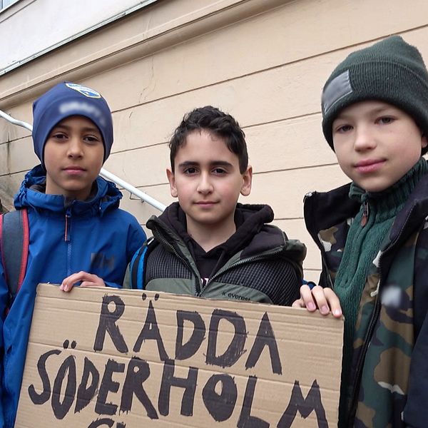 Tre pojkar framför plakat med texten: ”Rädda Söderholmsskolan”