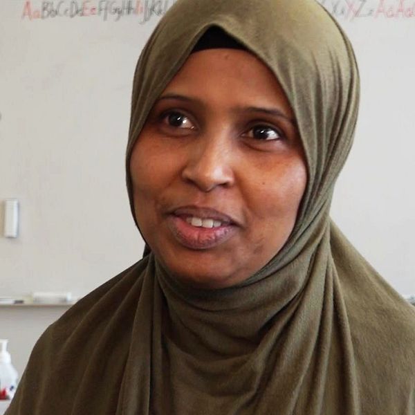Halimo Ahmed, en kvinna med mörkgrön slöja, står framför en whiteboard i ett klassrum.