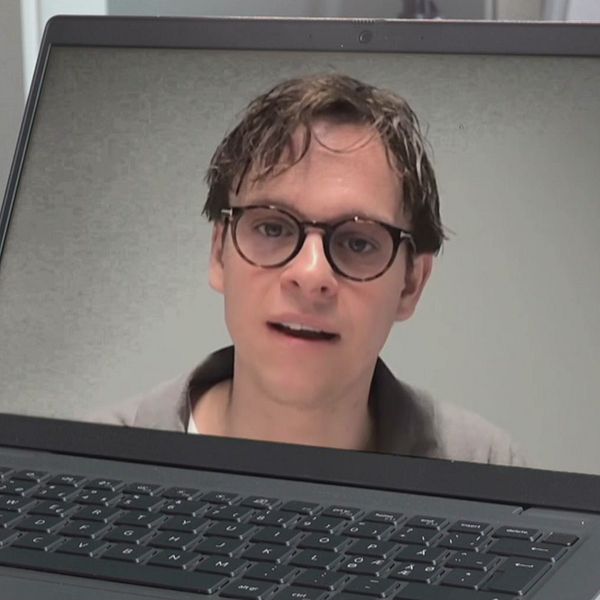 Man med glasögon och mörkt hår på bild i laptop