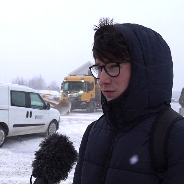 En kille står ute i snön med luvan på huvudet.