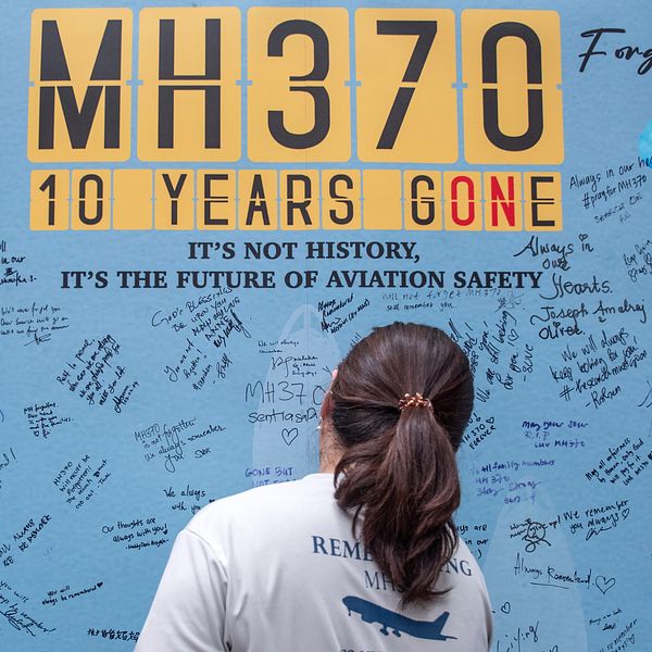 En anhörig till en av de saknade skriver på en minnesvägg tio år efter MH370:s försvinnande.