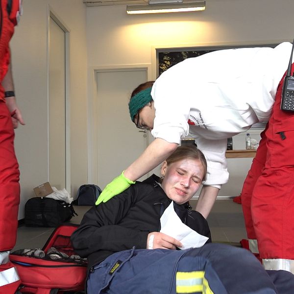 En medlem från Röda Korset hjälper en skadad tjej att lägga sig på en brits under en krisberedskapsövning.
