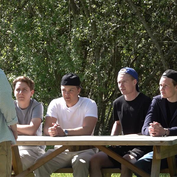 Fyra elever från Nobelgymnasiet sitter vid en bänk utanför skolan i Karlstad