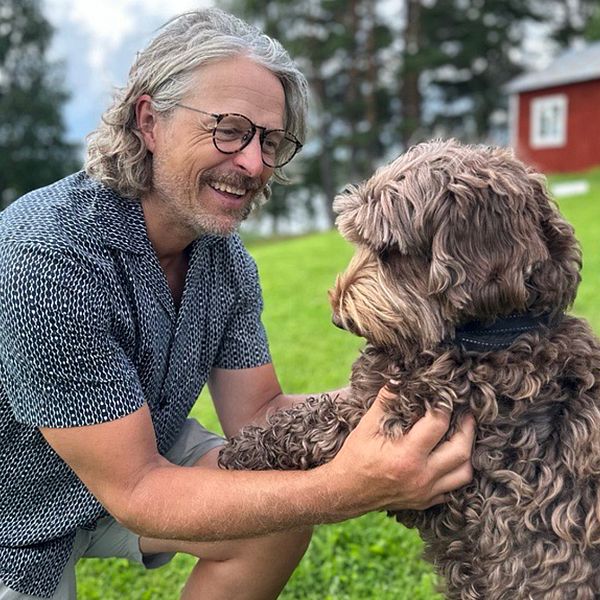 Per Höglund leker med en ljusbrun hund på en gräsmatta