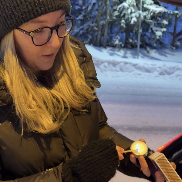 SVT:s reporter Stina Ahlinder tänder ett värmeljus vid bilen efter vägen.