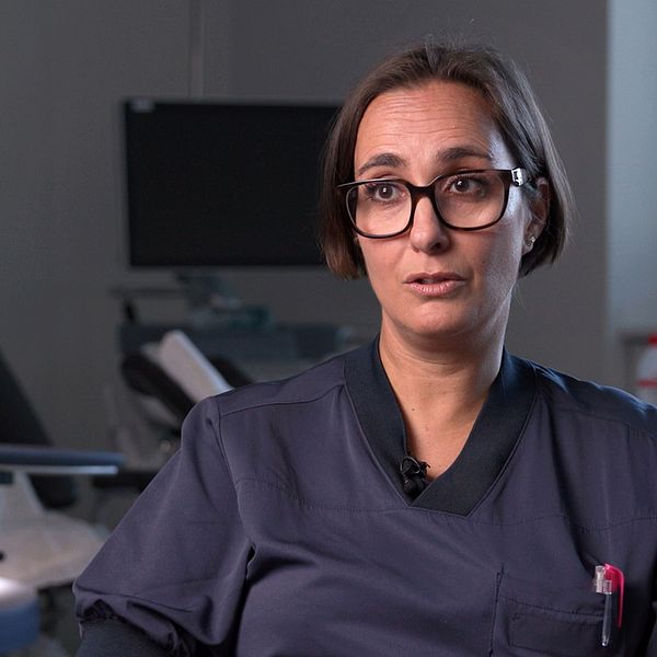 Emilia Rotstein, överläkare, l i sjukhusmiljö, svart uniform. Bakgrund med medicinsk utrustning.