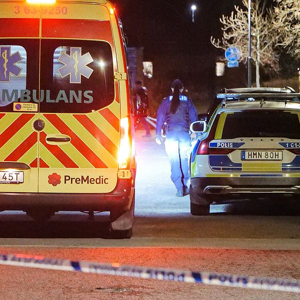 Ambulans och polisbil vid avspärrat område kvällstid.