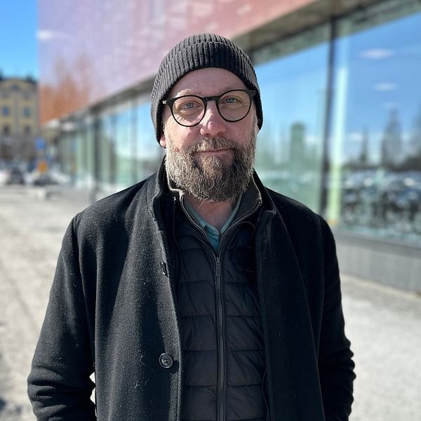 Joakim Åström i svart mössa, svart jacka och glasögon. Utanför Umestan i Umeå.