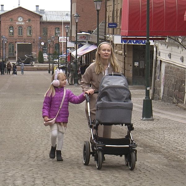 Mamma och barn med barnvagn går på stan