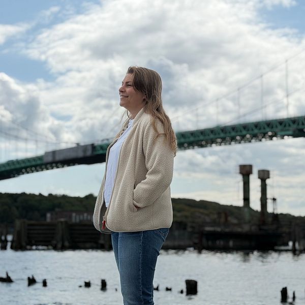 Sara står vid vattnet framför Älvsborgsbron och blickar ut över vattnet