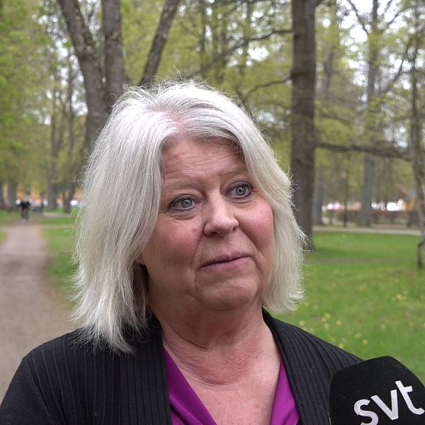 En kvinna intervjuas av SVT i en lummig park med grusgång och träd i bakgrunden.