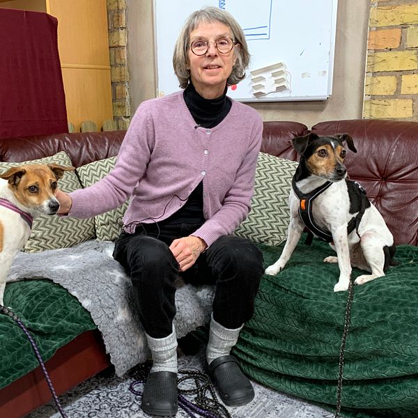 Hundinstruktören Pia Bildt Ström sitter i en soffa med sina två hundar
