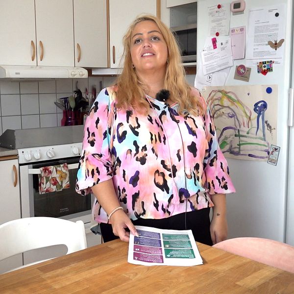 Madelene Eddaoui står vid sitt köksbord med en folder i handen.
