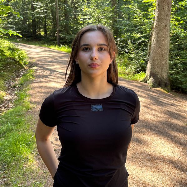 Elsa Hagman står på en skogsstig och tittar in i kameran