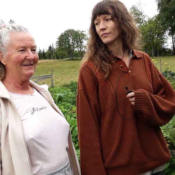 två kvinnor samtalar framför grönsaksodling
