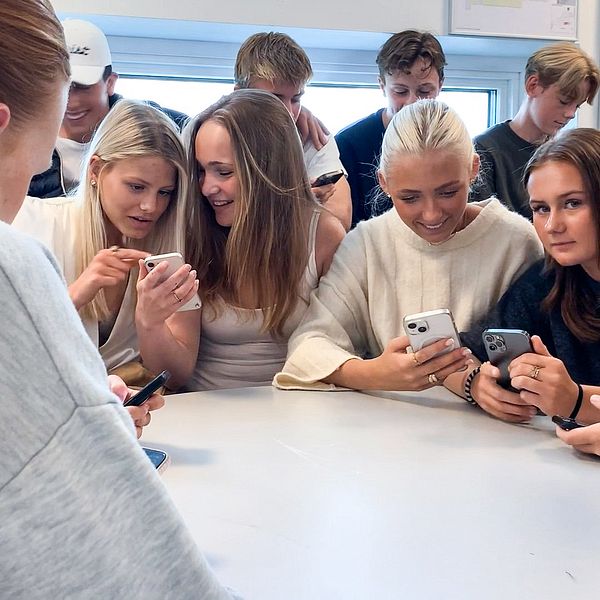 Bild på elever som sitter och kollar på mobilen