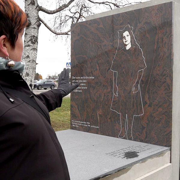 Mia Sörblom Groth pekar på monumentet över Agda Rössel.