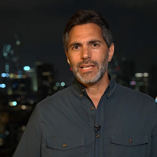 Person i mörk skjorta står framför en stadssilhuett på kvällen.