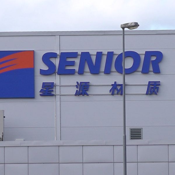Företagsbyggnad med ”Senior” logotyp och kinesiska tecken på fasaden.