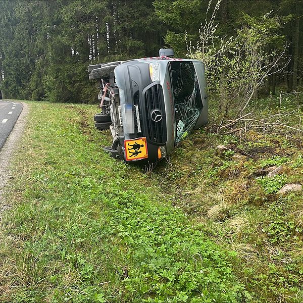 En minibuss har kört av vägen och landat på sidan i diket.