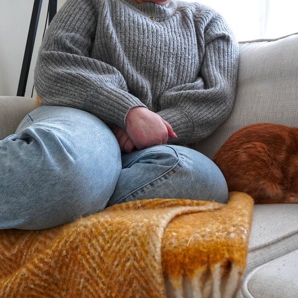 Kvinna sitter på soffa med katt.