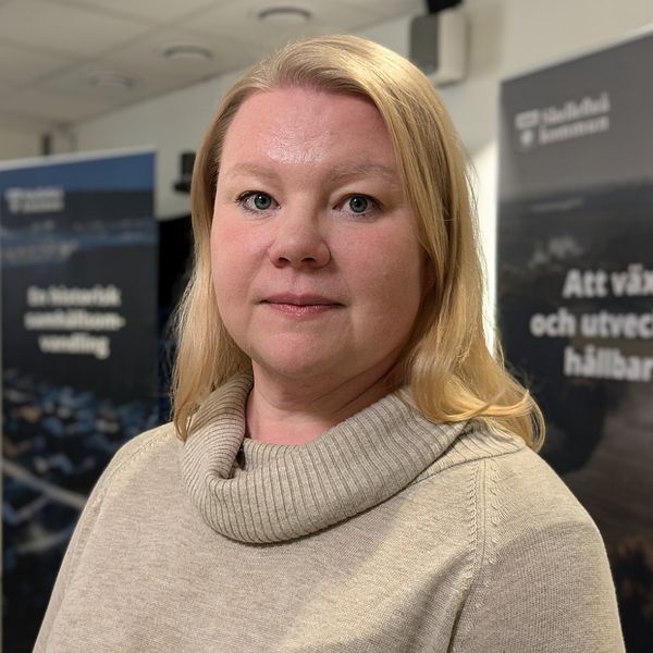 Ida Rönnblom står mitt i ett konferensrum i Skellefteå kommuns stadshus. I bakgrunden syns två att Skellefteå kommuns roll-ups som marknadsför kommunen.