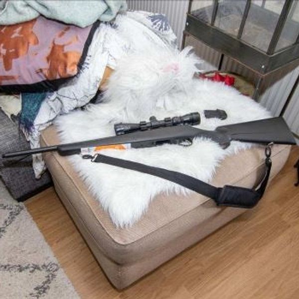 Ett jaktvapen ligger på en soffa i ett vardagsrum. Fotat i samband med polisens platsundersökning.