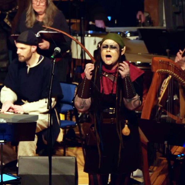 Flera musiker och en sångare uppträder tillsammans på en scen med olika instrument.