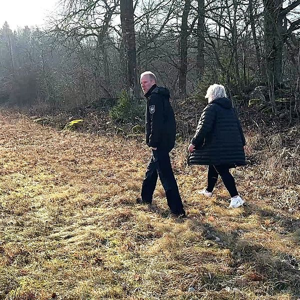 Två personer promenerar genom en höstlik skogsdunge.