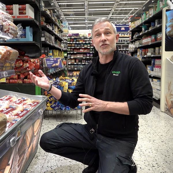 Markus Wahlgren sitter bredvid brödhyllor i en livsmedelsbutik.