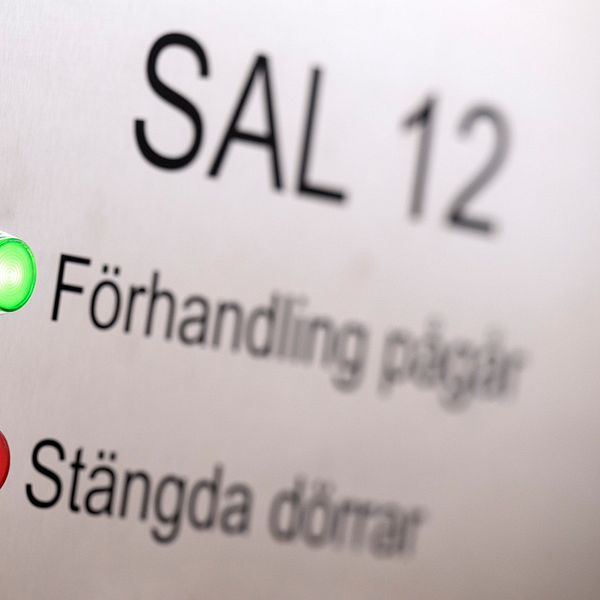 En skylt utanför en rättegångssal som informerar att förhandling pågår med ett tänt grönt ljus.