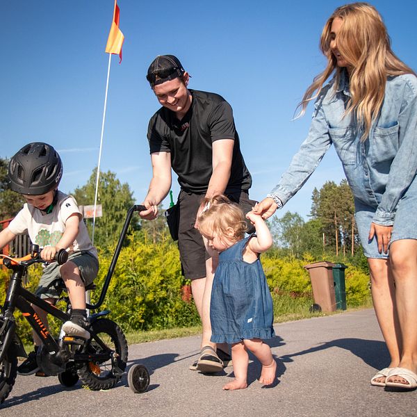 Småbarnsföräldrarna William och Vilma hjälper sina barn att cykla och gå på en väg bredvid familjens hus