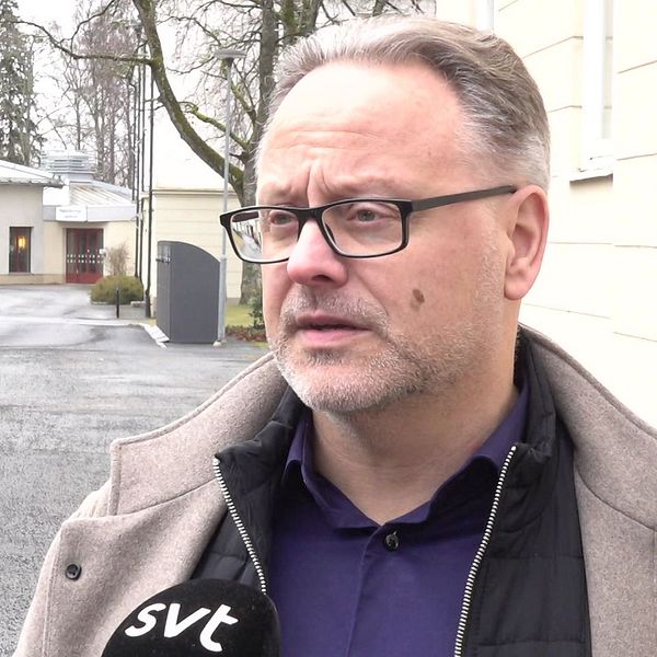 Intervju utomhus, SVT-mikrofon, byggnader i bakgrunden.