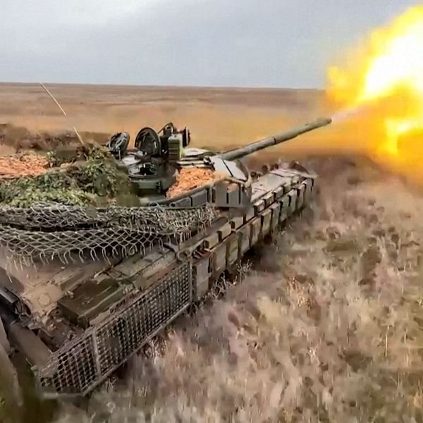 Stridsvagn som avfyrar kanon på ett öppet fält.