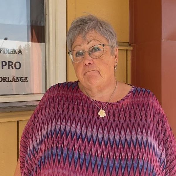Leena Voutilainen SVT:n haastattelussa, taustalla Finska PRO Borlänge -kyltti. Kvinna framför skylt med texten Finska PRO Borlänge
