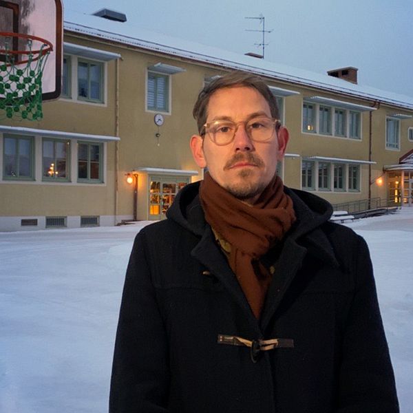 En politiker står på en skolgård i dalarna och tittar in i kameran