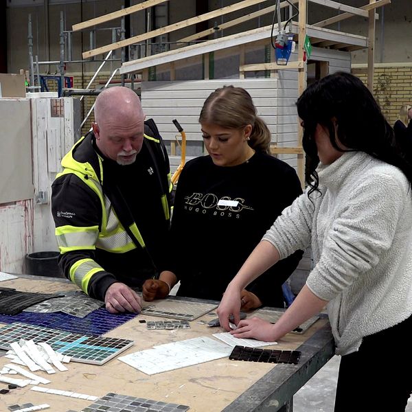 Alva Bousett-Nilsson och Ebbar Risberg får hjälp med mosaikplattorna
