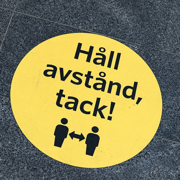 En dekal på ett golv där det står ”Håll avstånd, tack”