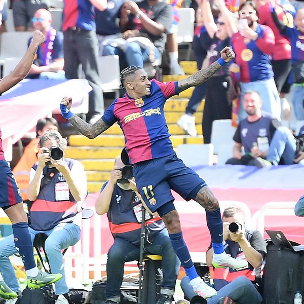 Barcelona-spelare firar mål framför jublande fans och fotografer vid sidlinjen.