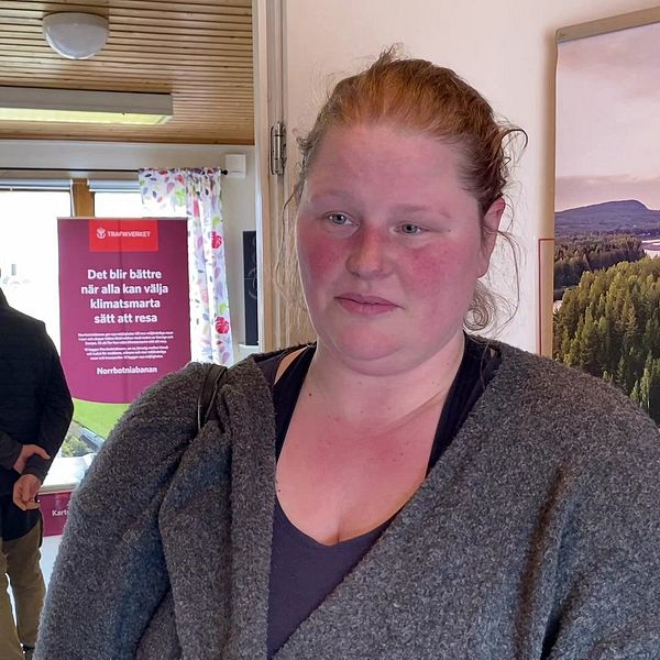 En rödhårig kvinna – fårbonden Johanna Larsson – intervjuas i rum med informationstavlor om Norrbotniabanan