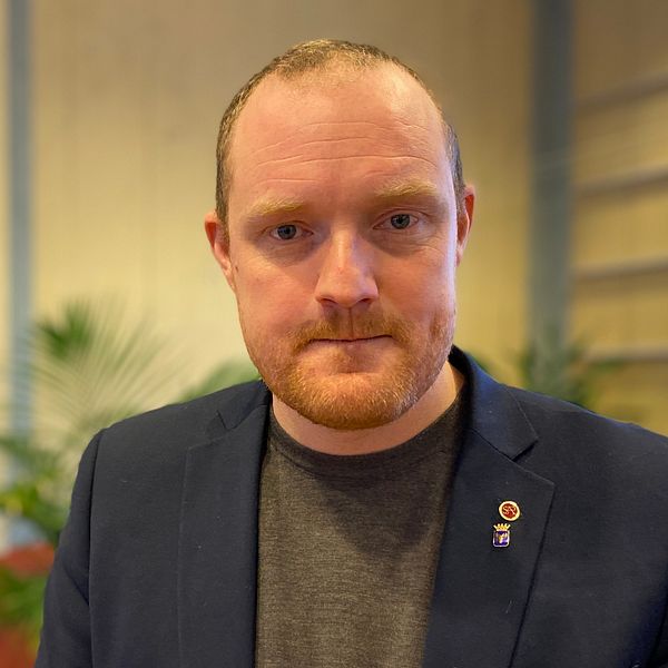 Östersunds kommunalråd Niklas Daoson, Socialdemokrat, står i ett rum. Klädd i mörkblå kavaj och grå tröja.