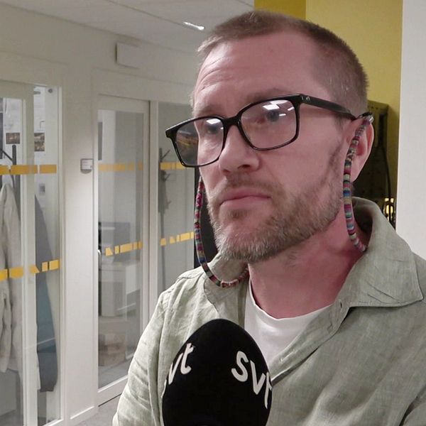 Henrik Mattsson, vd på företaget Titan står i ett kontorsutrymme och intervjuas av SVT. I bakgrunden syns glasdörrar som leder till ett annat rum, och där är också klädesplagg och kontorsmaterial synligt. Väggarna är målade i ljusa färger och rummet är väl upplyst.