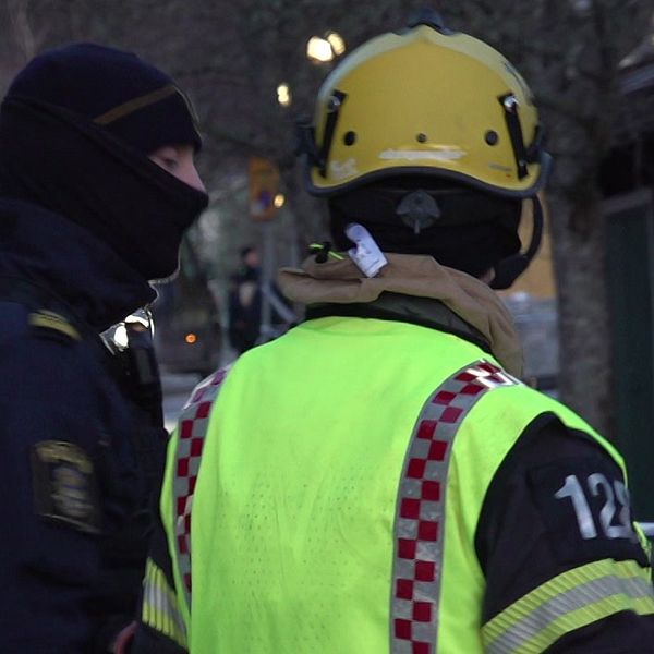 En polis och en person från räddningstjänsten står vid avspärrningarna vid explosionen i Strängnäs.