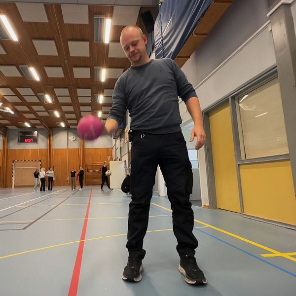 Johan Persson, ordförande i Torsby IK, står i en sporthall med en studsande boll i förgrunden.